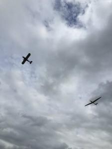 A plane and a glider flying against an overcast sky
