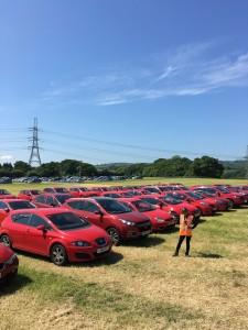 A masshal stands in front of rows of parked red vehicles in a field