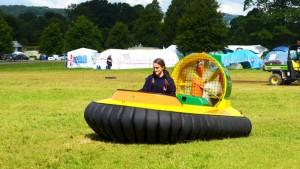 A person driving a yellow hover-craft in a field