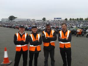 Four SEP marshals pose for a photo in front of parked vehicles