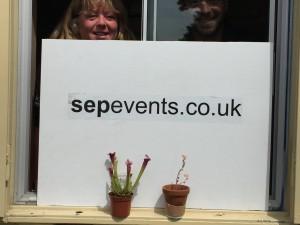 Two small plants in front of a sign that reads 'sepevents.co.uk'