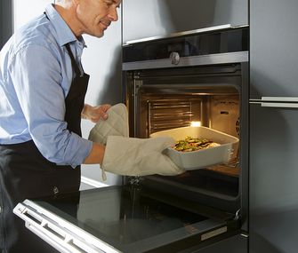 Mann stellt Gericht in hochgebauten Einbau-Backofen