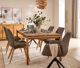 Helles Esszimmer mit großem Holztisch, passendem Sideboard und sechs grauen Polsterstühlen.