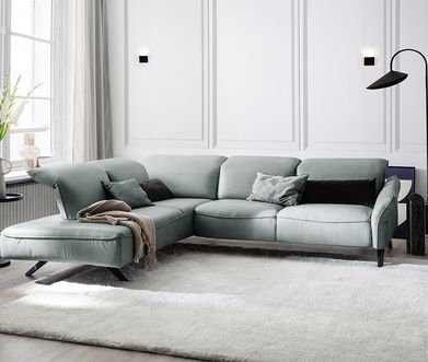 Glattes Leder wirkt etwas kühler als Rauleder. Blaugrüne Couch aus glattem Leder mit Kissen und Decke