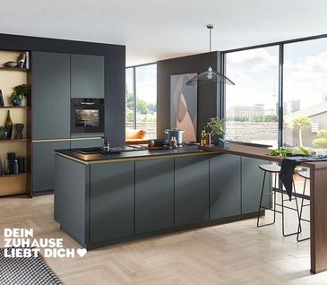 Inselküche in Mineralgrün mit Küchenzeile, Kücheninsel und Holztresen.