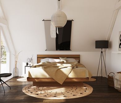 Aufgeräumtes Schlafzimmer mit Bettgestell aus Holz, dunklem Holzboden, Stuhl in Anthrazit