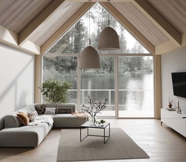 Chalet Wohnzimmer mit hellen Dachbalken, grauem Sofa, weißem Sideboard, kleinem Couchtisch und hellem Holzboden mit Blick auf See.