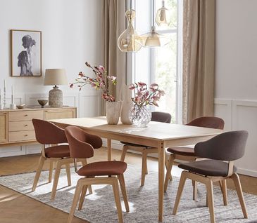 Rote und graue Stühle um einen Esstisch aus Holz im skandinavischen Design.