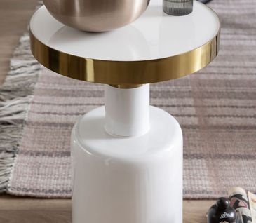 Beistelltisch aus Lack in weiß mit goldener Umrandung der Tischplatte, dekoriert mit einer Schale Popcorn und einem Glas Wasser.