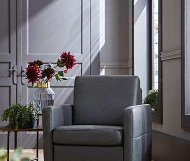 Grauer Loungesessel mit Beistelltisch aus Metallbeinen und Tischplatte aus Holz dekoriert mit Blumen