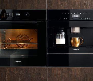 Küche mit eingebautem Kaffevollautomaten und einem Backofen