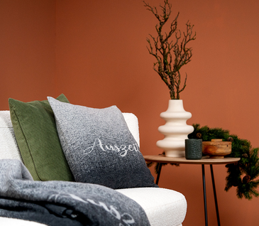 Wohntextilien Decke und Kissen auf hellem Sofa