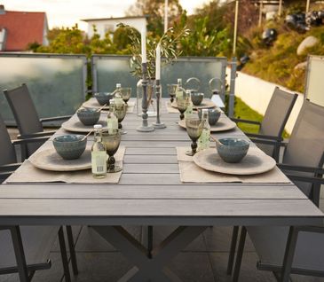 Terrasse mit gedecktem Tisch und Gartenstühlen.