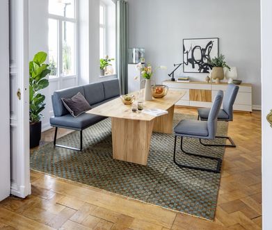 Esszimmer mit Freischwingern und Sitzbank in blau an einem hellen Holztisch.