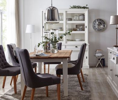 Graue Stoffstühle im Landhausstil mit Massivholz-Gestell an einem Esstisch im Landhaus-Stil.