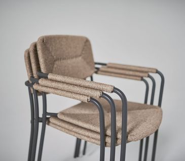 Gestapelte Gartenstühle mit brauner Sitzfläche und Rückenlehne.