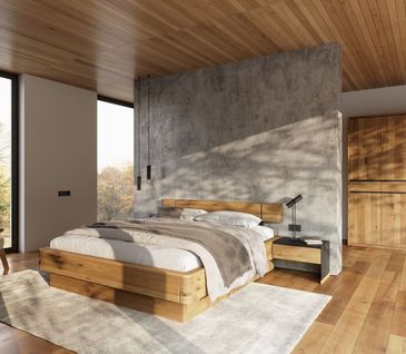 Bett aus massiver Eiche mit heller Bettwäsche und Kissen dekoriert.