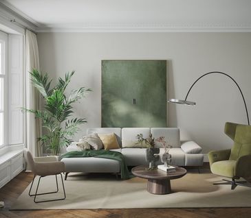 Minimalistisch eingerichtetes Wohnzimmer mit beigem Sofa und grünem Relaxsessel.