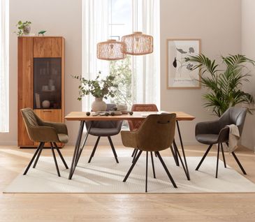 Modernes Esszimmer mit Esstisch aus Massivholz mit schwarzen Beinen an dem Polsterstühle aus unterschiedlichen Farben stehen.