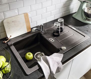 Dunkle Spüle mit einem Becken und Einhebelmischer in weißer Küche mit dunkler Arbeitsfläche