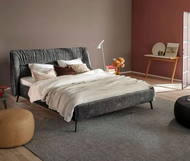 Zwei kleine Beistelltische in schwarz und rot neben einem grauen Polsterbett.