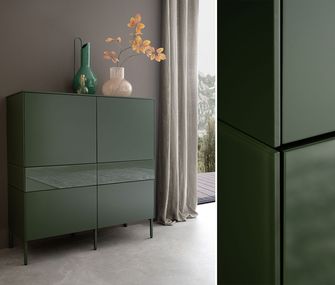 Grünes Highboard mit Deko vor grauer Wand.