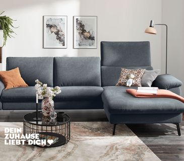 3-Sitzer-Sofa mit Longchair und Stoffbezug in Anthrazit in modernem Wohnzimmer.