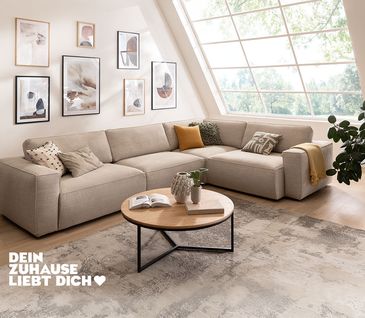 Minimalistisches Ecksofa mit beigem Stoffbezug in hellem Wohnzimmer, das in Beigetönen eingerichtet ist.