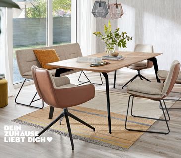 Helles Esszimmer mit Stühlen, Armlehnstühlen und einer Sitzbank der gleichen Kollektion mit Stoffbezug und Leder an der Rückenlehne.