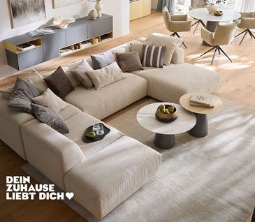 Sofa in U-Form mit beigem Stoffbezug in hellem und elegant eingerichtetem Wohnzimmer.