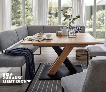 Klassisch eingerichtetes Esszimmer mit hellgrauer Eckbank und passenden Stühlen um Holz-Esstisch.