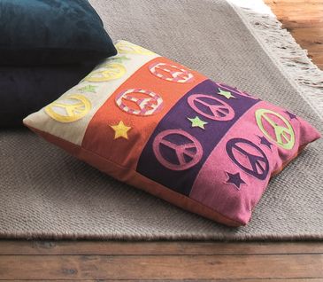 Buntes Kissen mit dem klassischen Peace-Muster in Gelb, Rosa und Lila