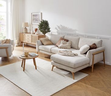 Wohnzimmer im Skandi-Stil mit beigem Sofa und Sideboard aus hellem Holz.
