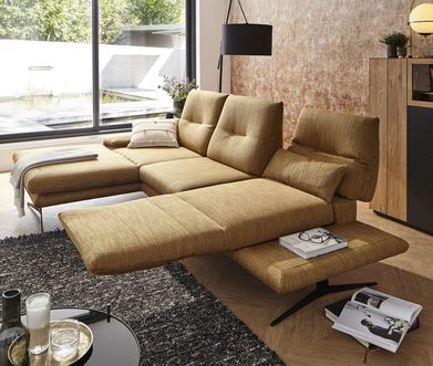 Braunes Ecksofa mit aufgebauter Relaxfunktion neben einer schwarzen Stehleuchte