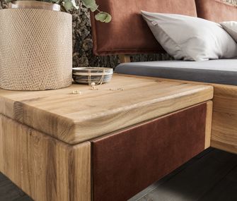 Bild zweiter Nachttische desselben Modells aus massiver Eiche, die Schubladenfront einmal in Granitoptik und einmal in Kupfer