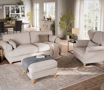 Wohnzimmer im Landhausstil mit beigem Sofa und Ohrensessel.