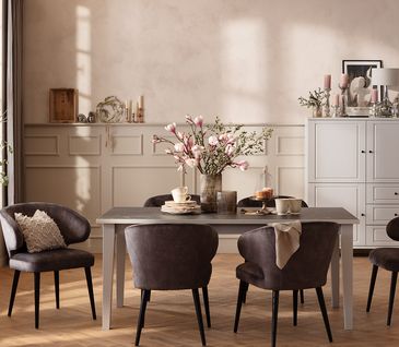 Esszimmer im Landhausstil mit weißem Esstisch, passendem Highboard und verzierten Wänden.