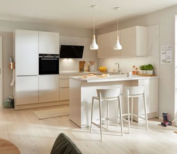 Moderne U-Küche in Beige mit Tresen und Hockern sowie offenem Essbereich.