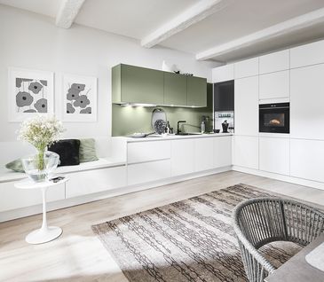 Wohnküche in Weiß und Salbeigrün mit Essbereich und Sitzecke.