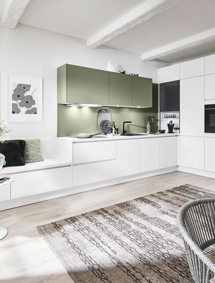 Wohnküche in Weiß und Salbeigrün mit Essbereich und Sitzecke.