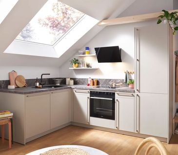 Eckküche mit beigen Fronten in Raum mit Dachschräge.