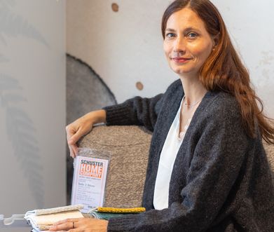 Nicole Zweig sitzt auf einem Sofa im Möbelhaus und zeigt die Stoffauswahl zur Konfiguration.