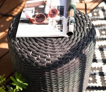 Grauer Outdoorhocker mit einer Zeitschrift und Sonnenbrille.