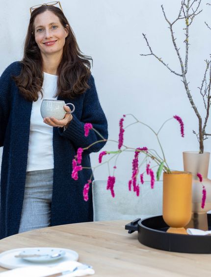 Interior Stylistin Nicole Zweig steht vor rundem Esstisch.