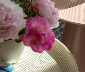 Detailbild von zwei Beistelltischen in Beige und Rosa, dekoriert mit Blumen.