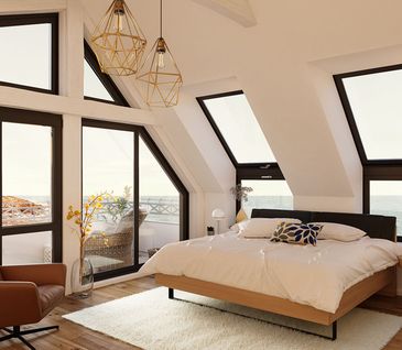 Brauner Ledersessel und Massivholzbett in einem hellen Loft am Strand