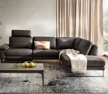 Warme Töne wie ein sattes Moccabraun bringen Eleganz in dein Wohnzimmer. Modernes Leder-Ecksofa in Farbe Mocca, hellgrauem Teppich und Couchtisch.