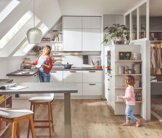 Küche im Dachgeschoss mit räumlicher Trennung zum Wohnzimmer mit Mutter und Kind
