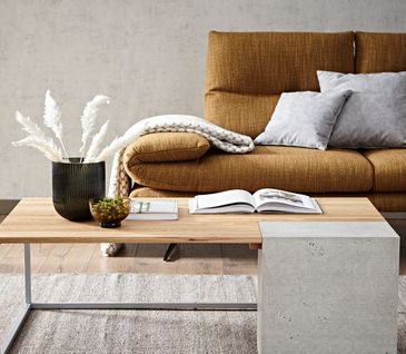 Couchtisch aus Massivholz und Beton vor goldenem Sofa