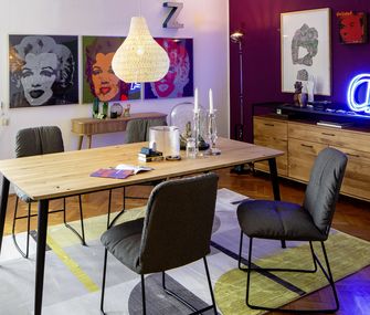 Esstisch mit Stühlen mit Warhol-Bildern an den Wänden und Leuchtschild